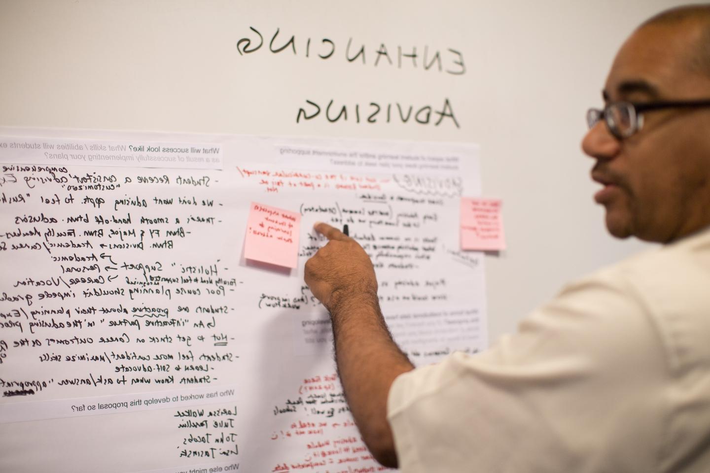 wilson terrell places a post-it note on a whiteboard about advising