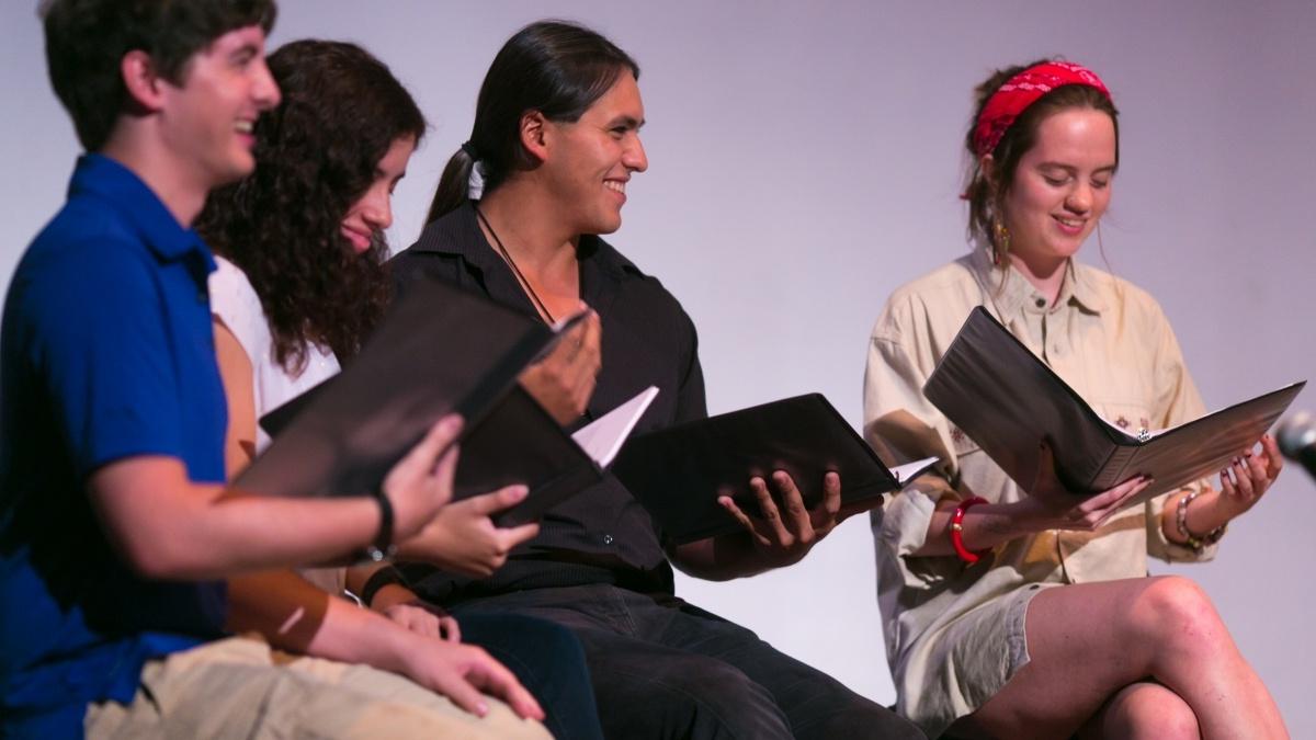 diverse group of people smiling and reading from a folder