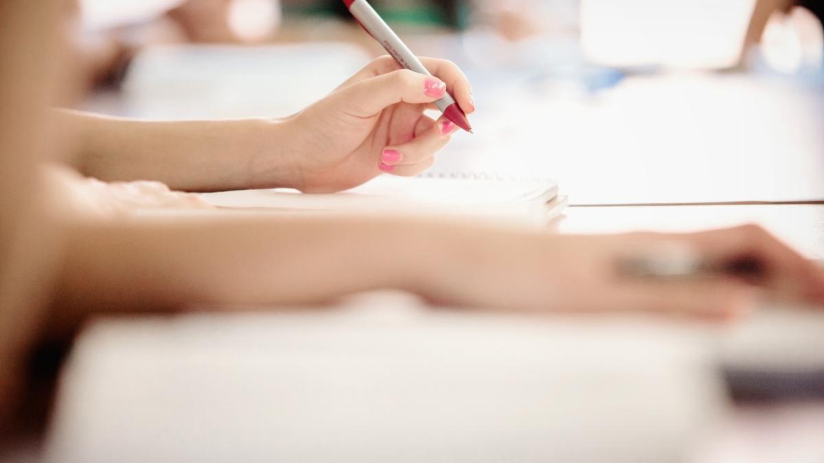 hand holds a pen to write in a notebook